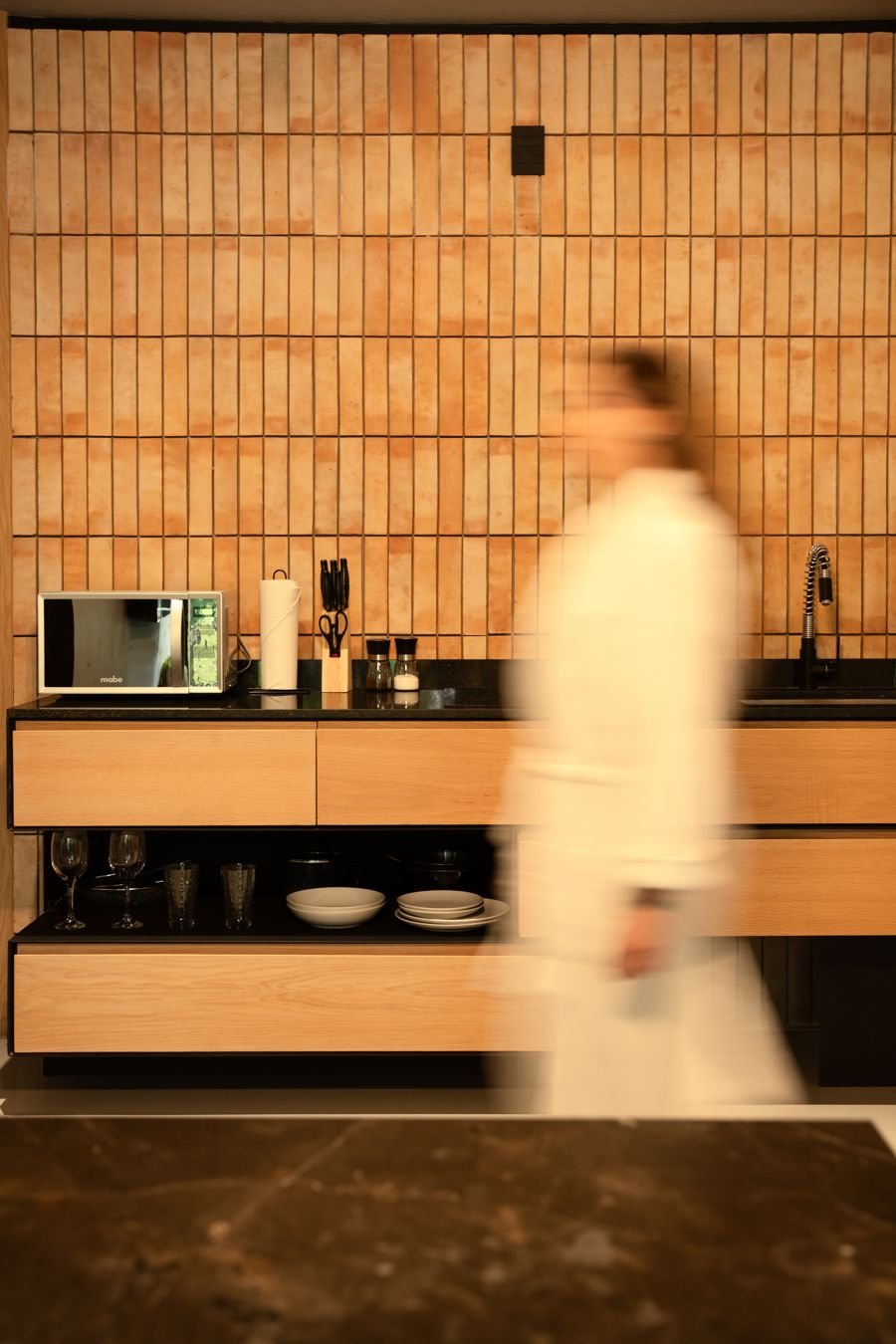 Kitchenette with terracotta brick wall and oak cabinets