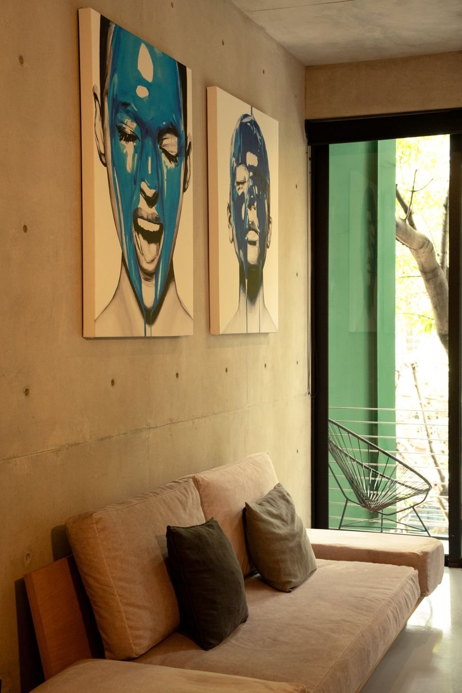 Living room with linen sofa, blue portraits and a balcony to the trees